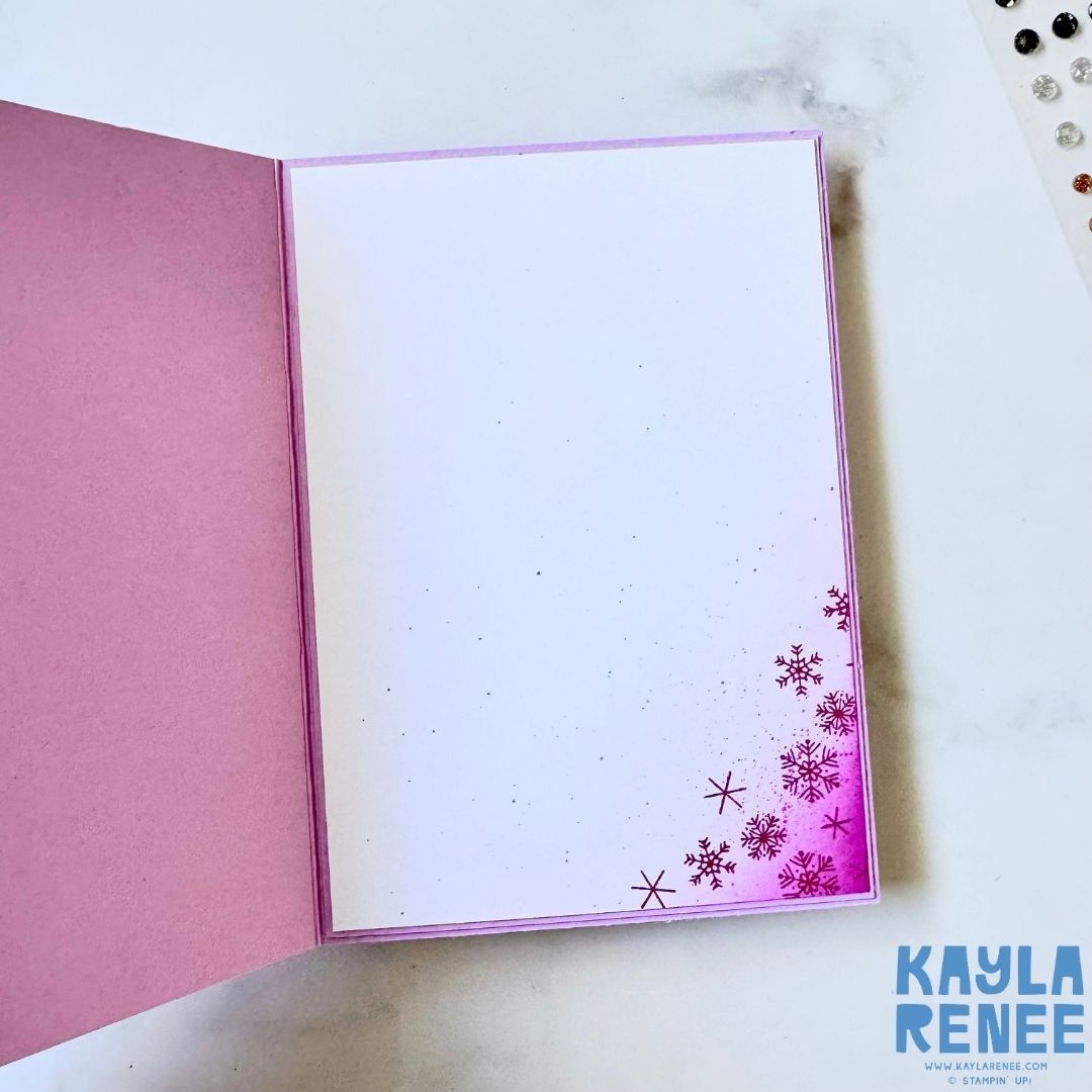 Inside of the handmade Christmas card with a clean white panel softly ink-blended in pink. The bottom corner is decorated with stamped pink snowflakes for a coordinated finish.