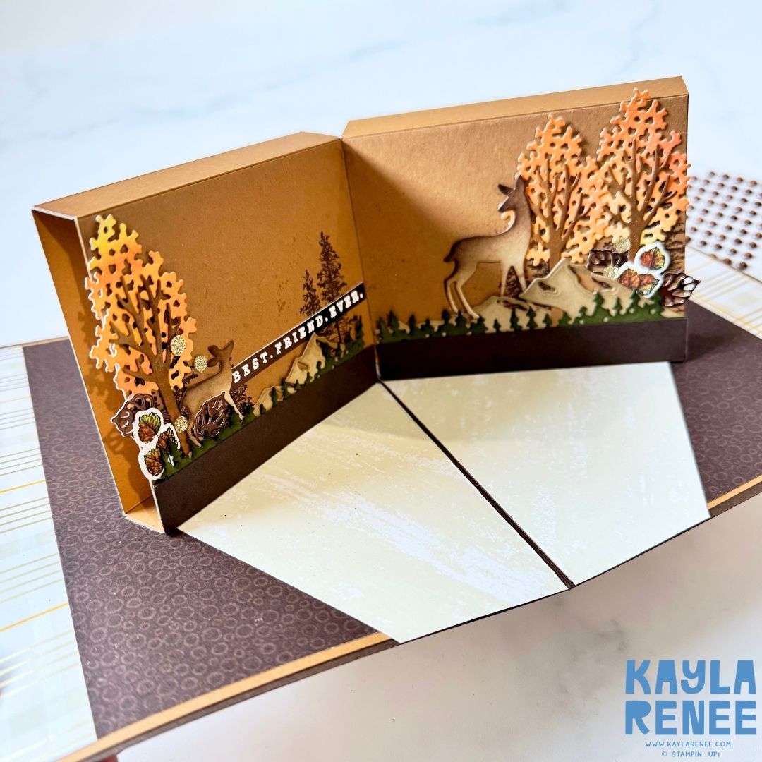 Inside of the pop-up card revealing a 3D forest scene with trees, a deer, and woodland accents. Layers of paper create depth with the phrase ‘Best. Friend. Ever.’ along the left panel.