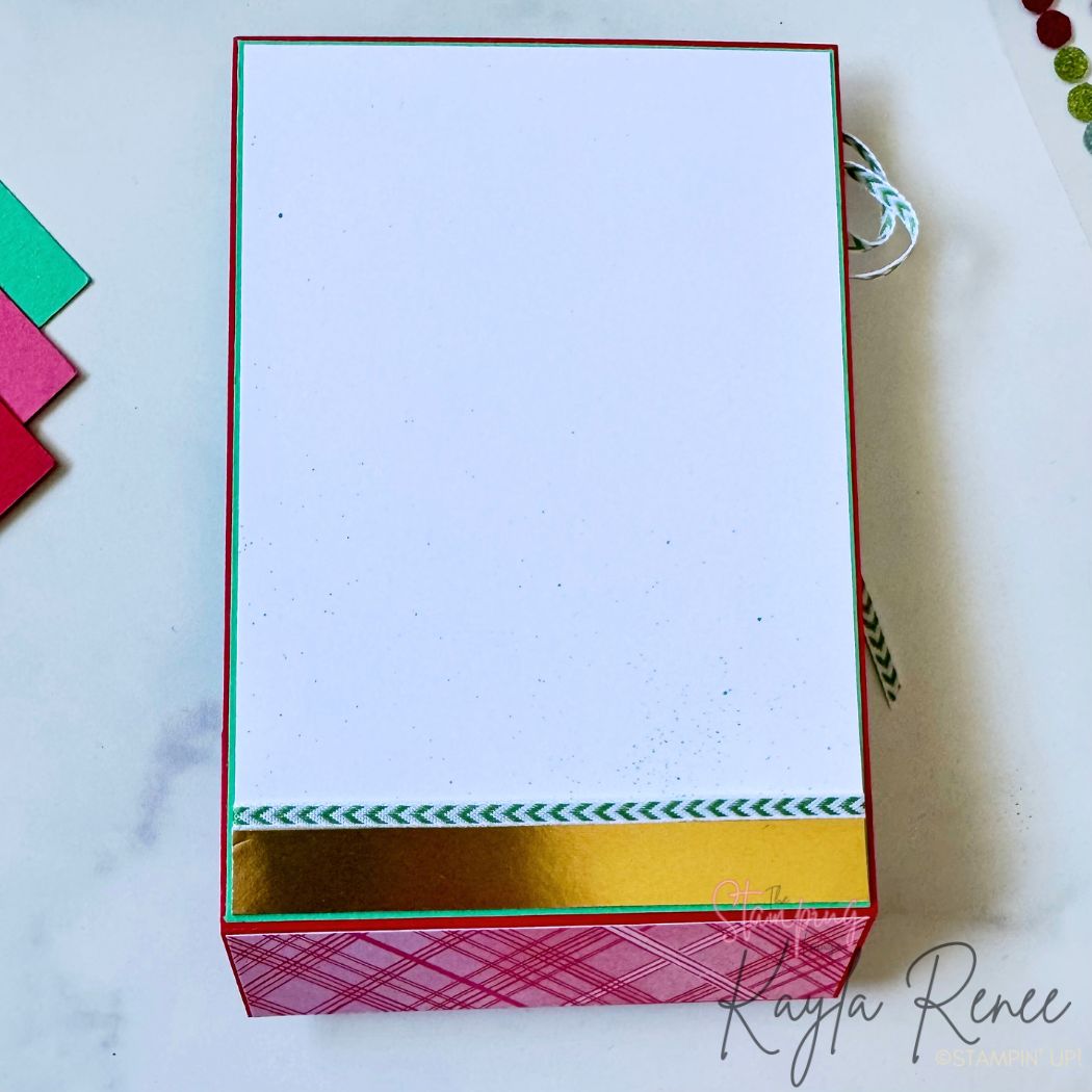 Inside of handmade Christmas card featuring a clean white writing panel bordered with a strip of gold foil and green patterned trim. The bottom step section has red plaid patterned paper.