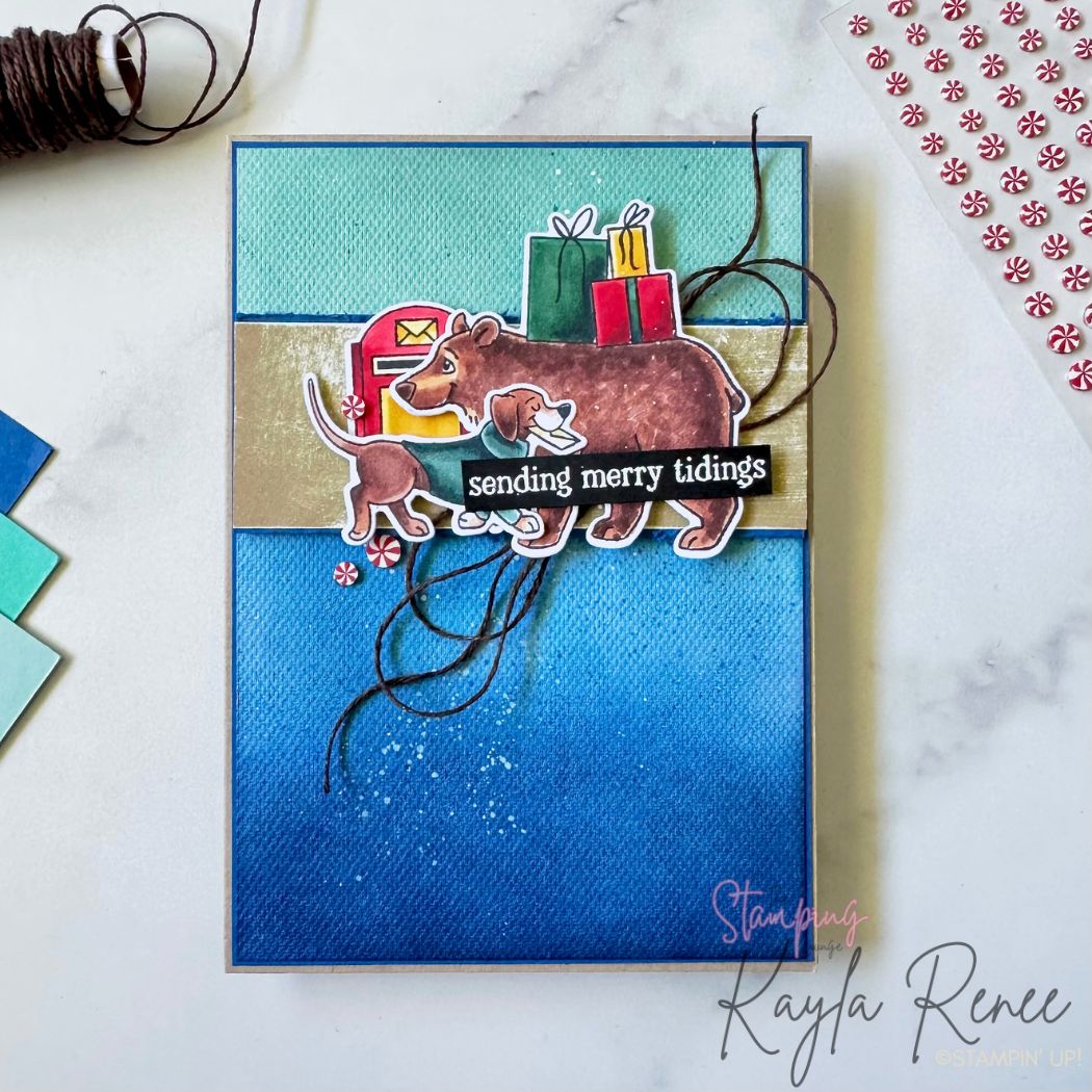 Handmade Christmas card with a blue ombré textured background and layered stamped images of a bear and puppy delivering mail, with presents and a mailbox using the Stampin’ Up! Jolly Delivery stamp set. The sentiment reads 'sending merry tidings' on a black strip. Peppermint embellishments and brown twine add festive detail.