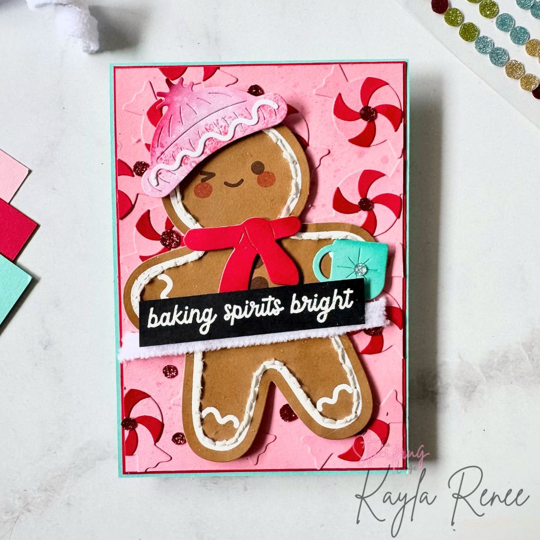 Handmade Christmas card featuring a large die-cut gingerbread man on a pink peppermint-themed embossed background. The gingerbread man wears a pink hat and red scarf, holding a turquoise mug. White faux frosting details and sparkling accents create a festive look. Sentiment reads “baking spirits bright.” Bright, modern holiday card created using Stampin’ Up! paper craft supplies.