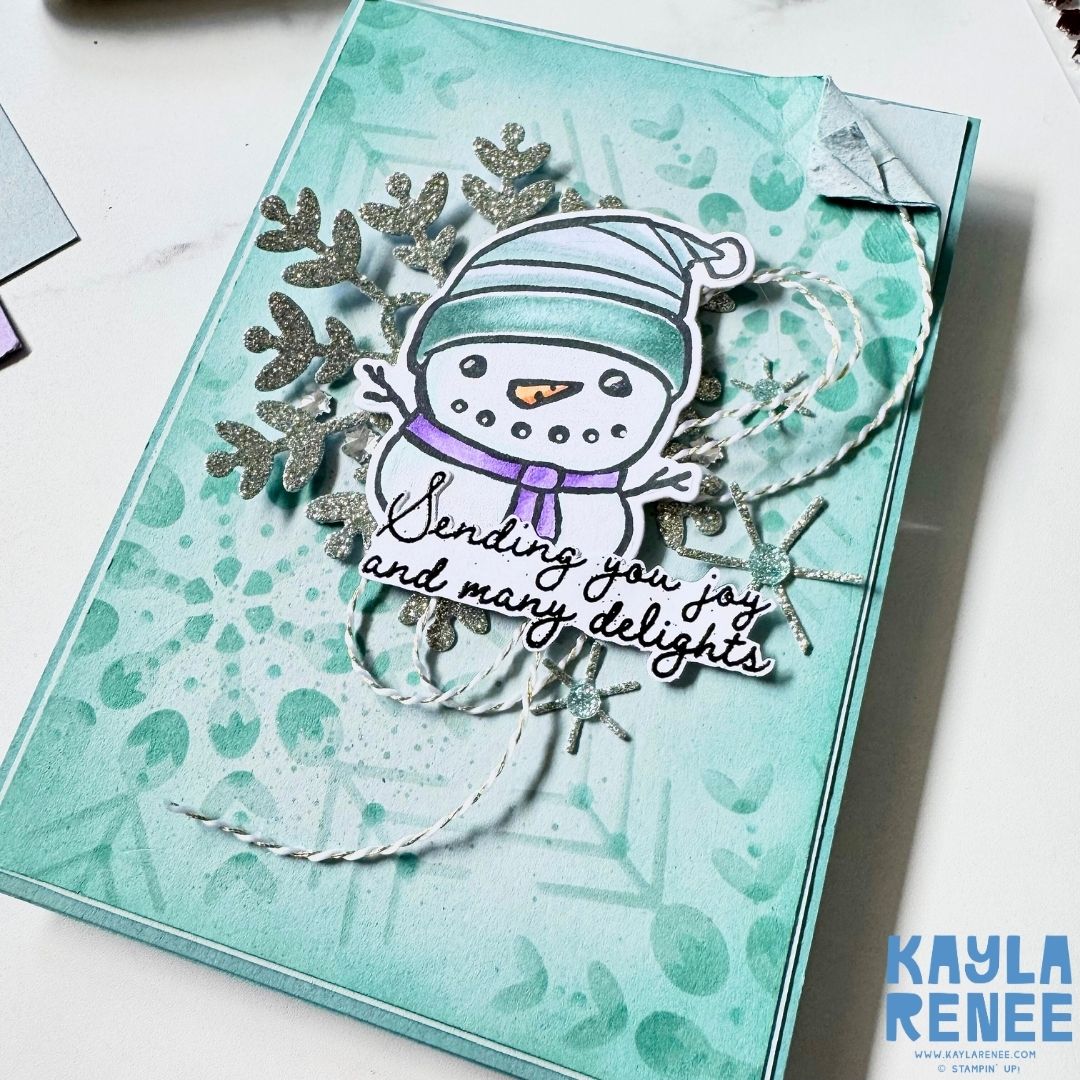 Angled view of Christmas card featuring snowman coloured with Stampin' Blends and glittery snowflake
