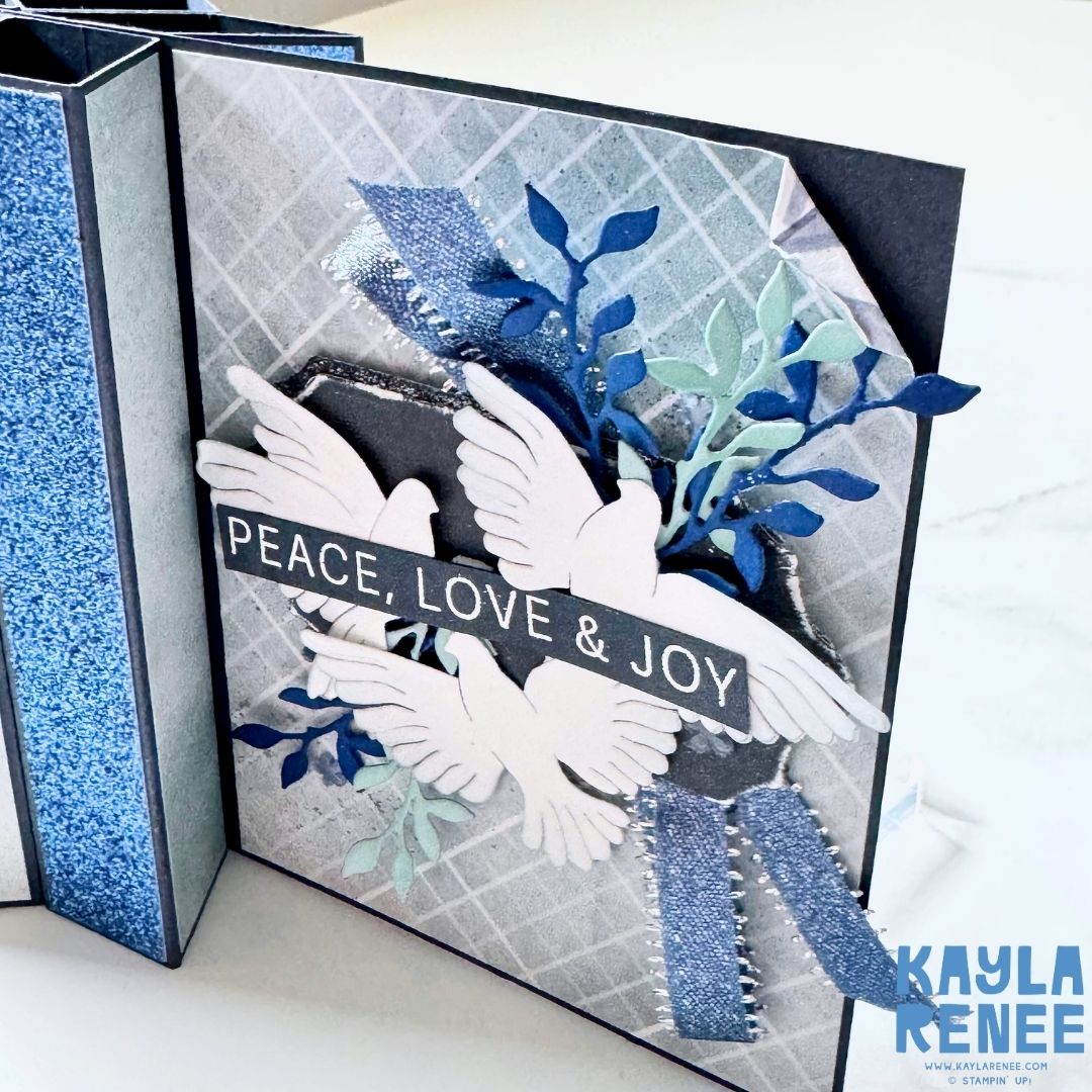 Side view of a star fun fold card design by Kayla Renee featuring the Stampin’ Up! Peaceful Gardens suite. Highlights include glimmer paper panels, 3D folded structure, and white doves with navy and mint foliage embellishments.