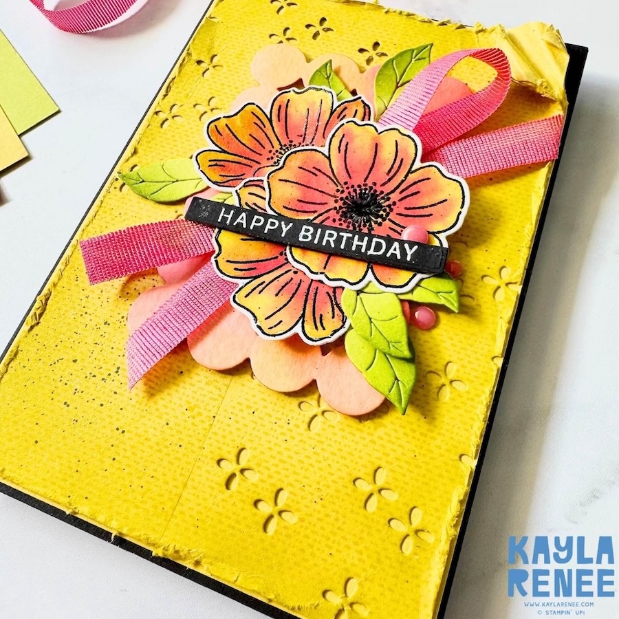 Close-up detail of yellow floral birthday card showing dimensional die cuts, ink-blended petals, ribbon loops and textured background.