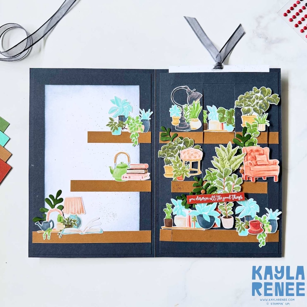 Opened multi-panel slider card showing multiple interactive panels with shelves of potted plants, books, a lamp, and a cozy chair, arranged on a dark grey background with warm brown accents.