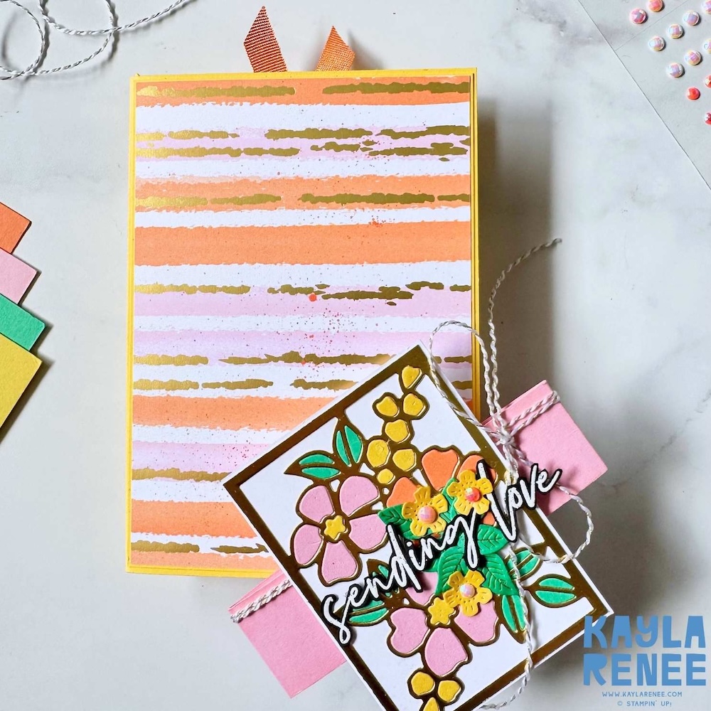 Closed card layout showing striped background paper, layered floral die cuts and dimensional “Sending love” greeting tied with twine.