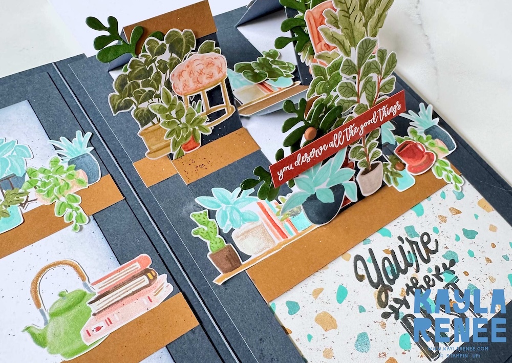 Angled view of the interactive slider card highlighting layered plant shelves, dimensional die-cut foliage, and movable panels creating depth and movement.