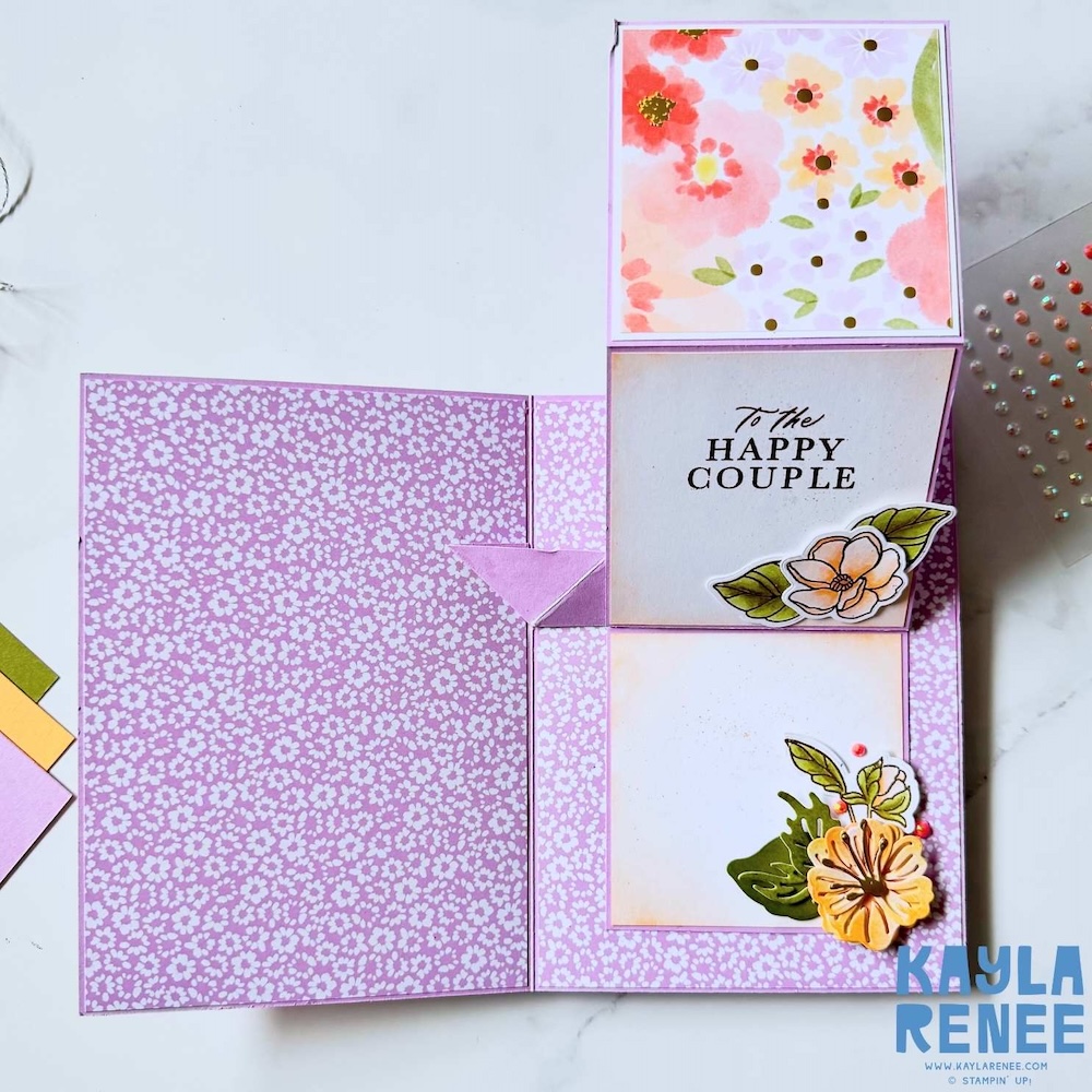 Interactive expanding pop-up card opened to reveal vertical panel with “To the Happy Couple” sentiment and coordinating floral decorations.