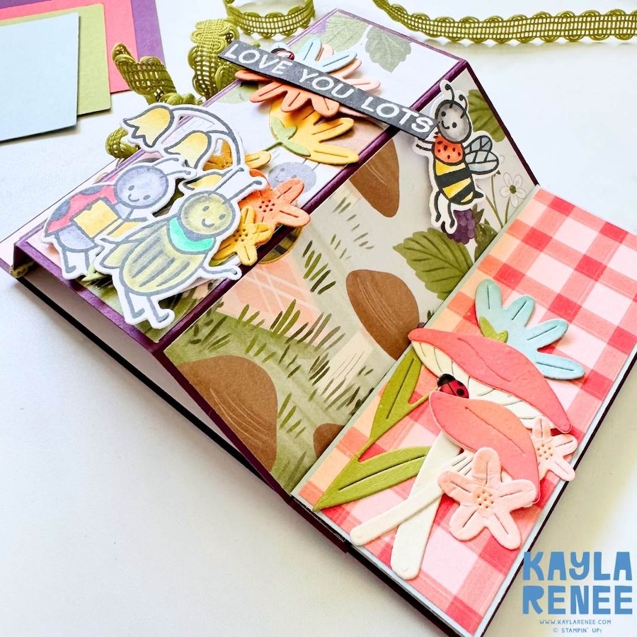 Angled close-up of interactive bay window card highlighting layered bugs, flowers, and mushrooms with bright colours and dimensional die-cut elements.