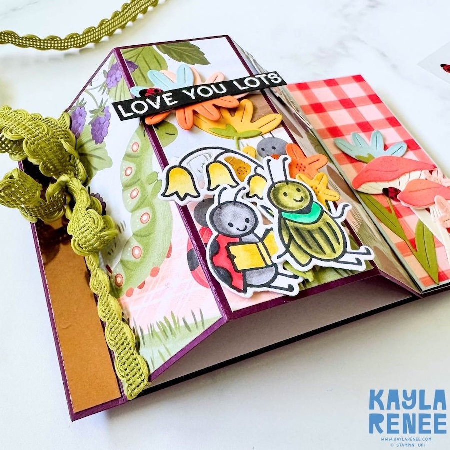 Side view of bay window fold structure showing depth and dimension, with ribbon closure and layered insect embellishments across the front panels.