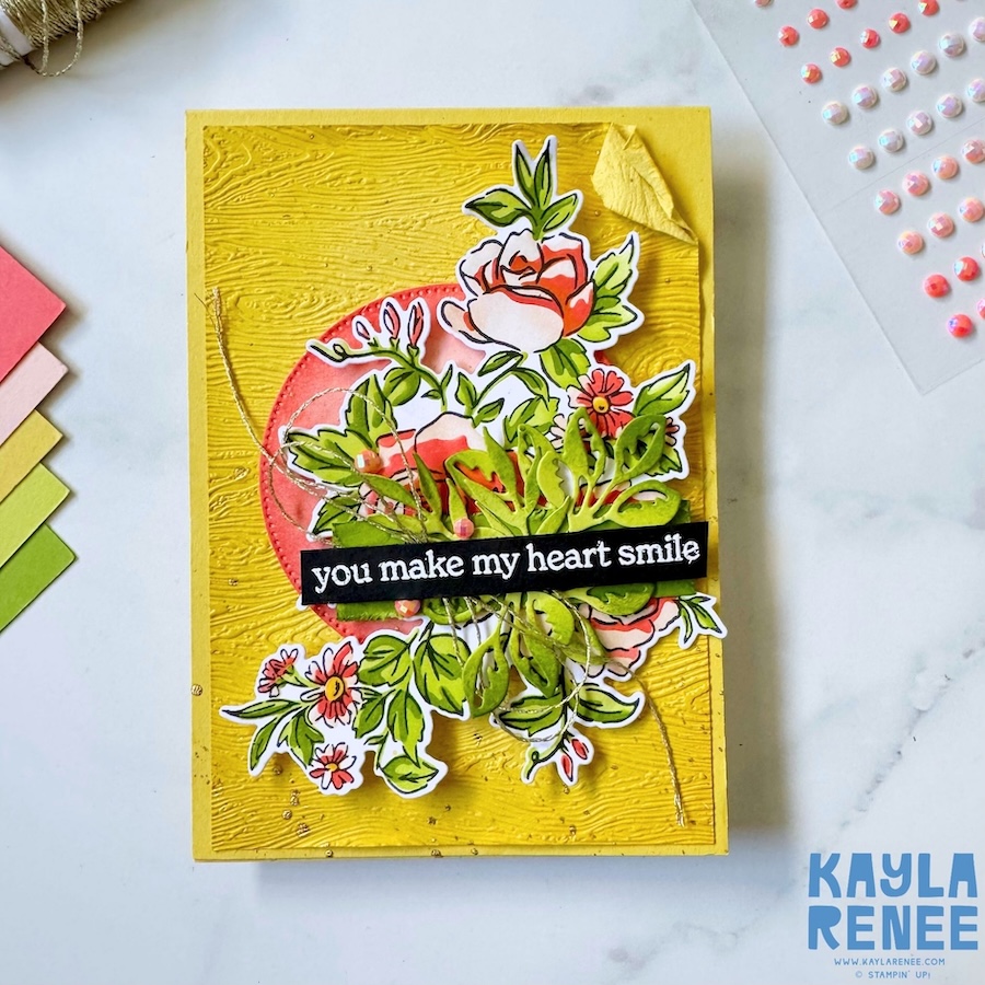 Full front view of a bright yellow handmade card using the Stampin’ Up! Layers of Beauty bundle, showcasing a layered floral arrangement over a coral circle with die-cut leaves, embellishments, and a bold black sentiment strip.