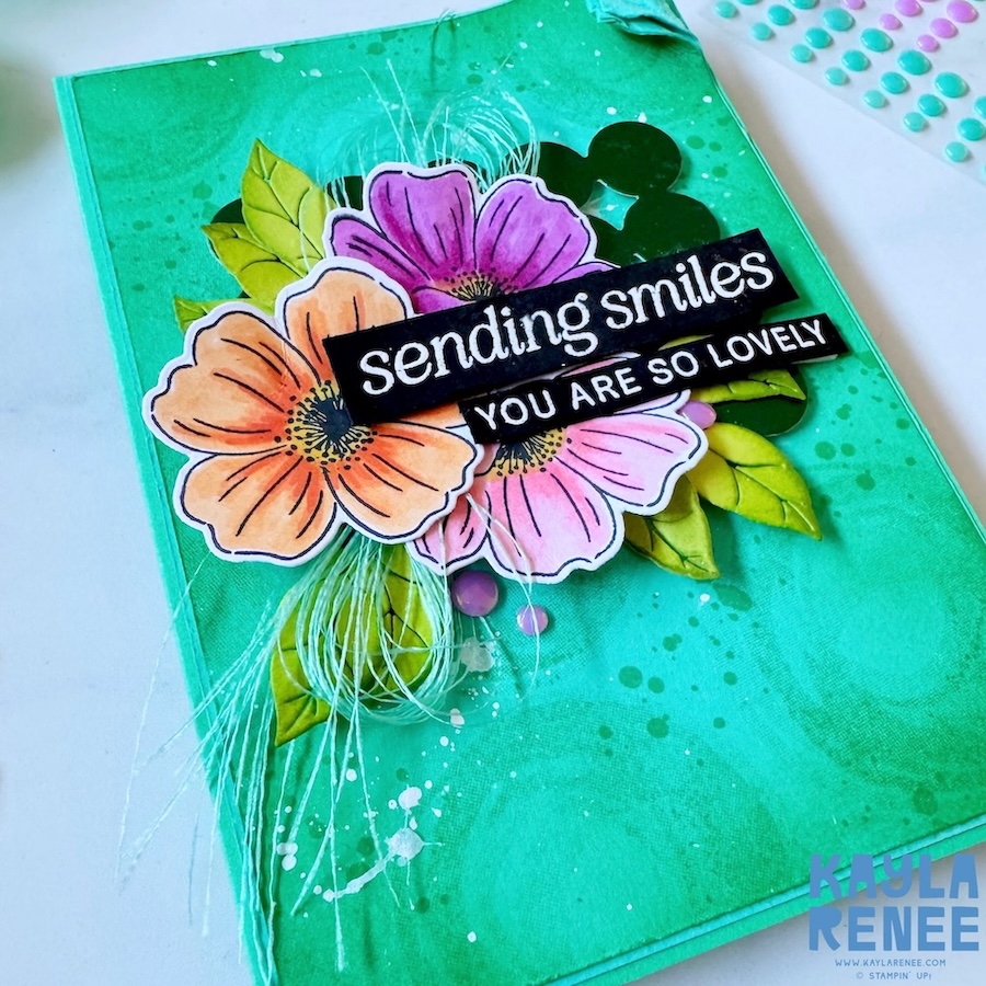 Angled close-up highlighting dimensional floral cluster with pink, peach, and purple blooms, leafy accents, and textured ink-blended background using Swirled Designs stamp set.