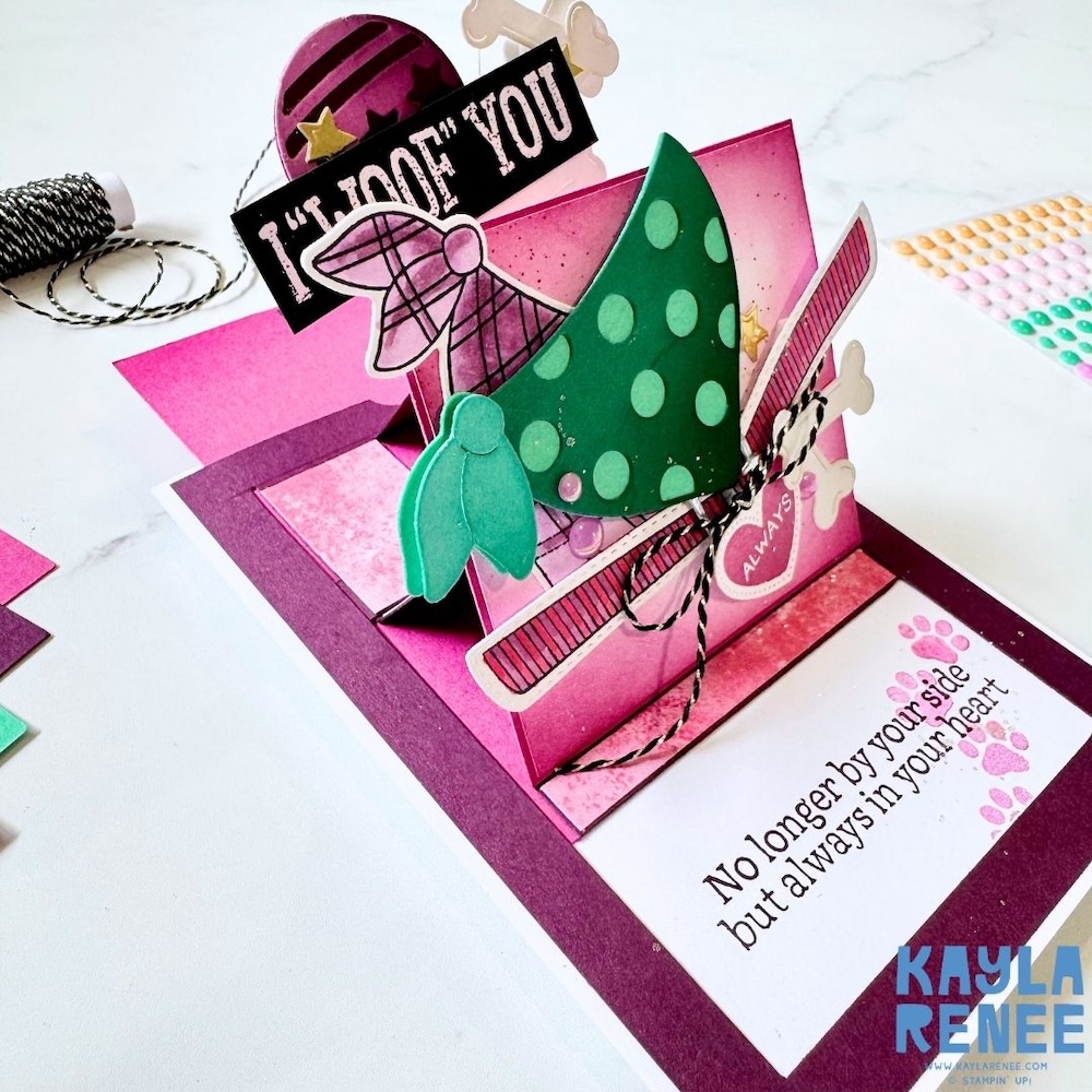 Close-up angled view of the pop-up slider mechanism, showing layered elements including the green polka dot dog, ribbon details, and stamped sympathy sentiment.