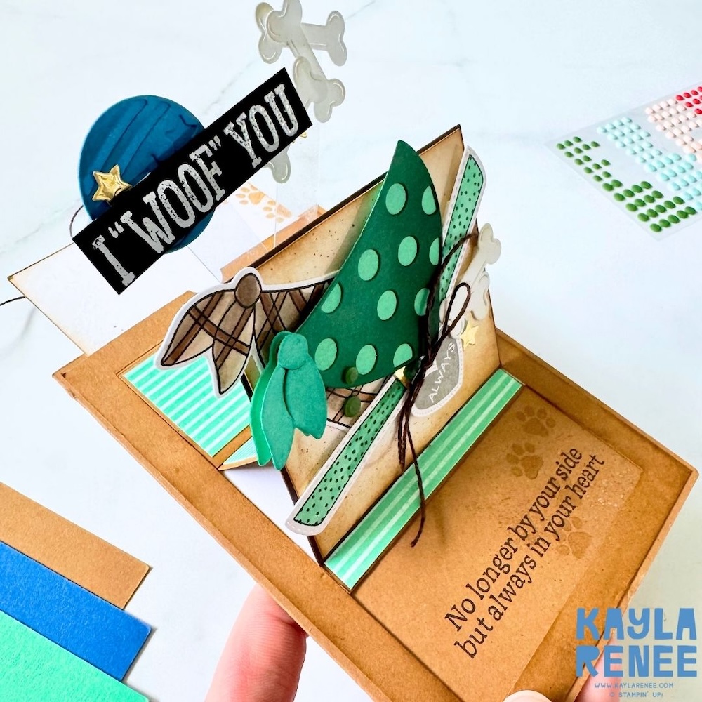 Detailed view of dimensional embellishments including die-cut bones, heart tag with “always,” twine, and textured inking on a multi-panel slider card.