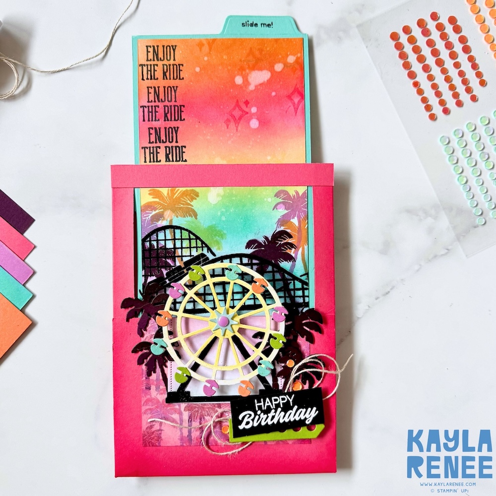 Interactive Stampin’ Up! Beach Boardwalk suite slide and surprise card with the pull tab extended, revealing a colourful gradient sky with palm trees and repeated “Enjoy the ride” stamped sentiment.