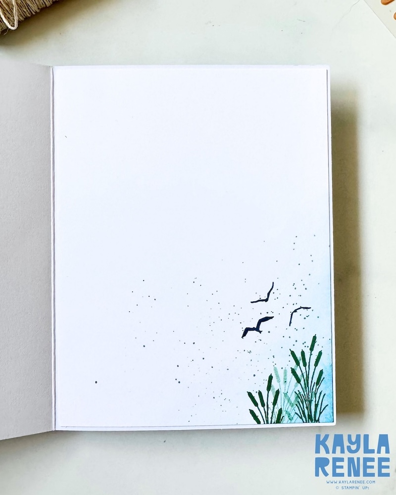 Inside view of a handmade masculine card created with the Stampin’ Up! Lakeside Retreat Paper Pumpkin Kit, featuring simple stamped reeds, flying birds, soft splatter effects, and a clean white writing panel.