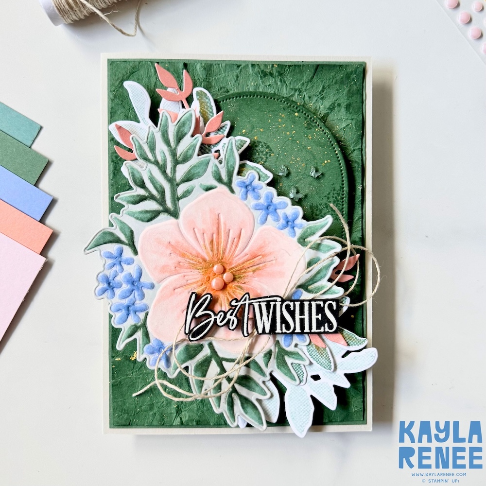 Handmade floral card created with the 2026–2028 Stampin’ Up! In Colors and the Opulent Oasis bundle, showcasing layered die-cut foliage, pastel blue flowers, gold splatter details, dimensional embellishments, and a textured green mixed media background.