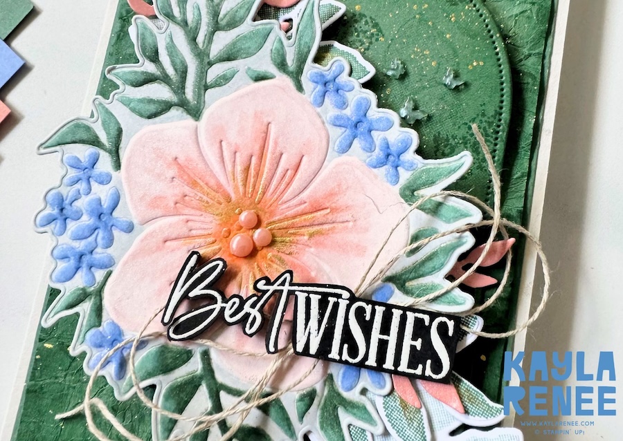 Close-up of a handmade card using the 2026–2028 Stampin’ Up! In Colors and the Stampin’ Up! Opulent Oasis bundle, featuring soft pink florals, layered greenery, twine accents, and a bold “Best Wishes” sentiment over a textured green background.
