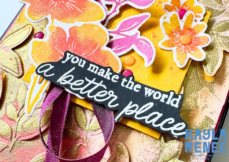 Detailed close-up of a floral card made for Global Design Project #GDP550 using the Stampin’ Up! Garden Poetry Suite. The image showcases layered multi-colour stamped flowers, bright pink foliage, ribbon accents, enamel dots, and the sentiment “You make the world a better place,” set against a textured background created with dry embossing and heat embossing techniques.
