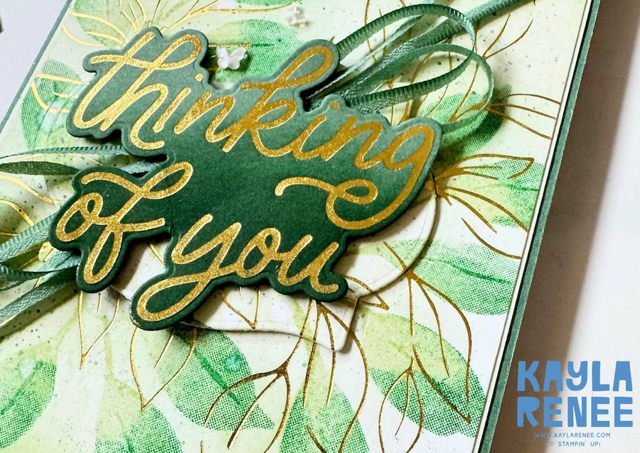 Handmade thinking of you card created using the Stampin’ Up! Botanical Glow and Classic Greetings hot foil products. The card features gold hot foiled botanical images layered over soft green ink blending, with a large gold foiled "Thinking of You" sentiment as the focal point. Finished with layered ribbon, delicate embellishments, ink splatter, and dimensional details for an elegant botanical design.