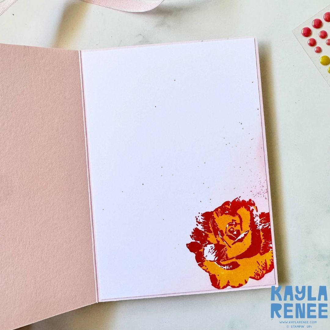 Inside of a handmade Stampin’ Up! Begonia Belle card with a white writing panel and a bright yellow and red stamped rose decorating the lower right corner against a soft pink card base.