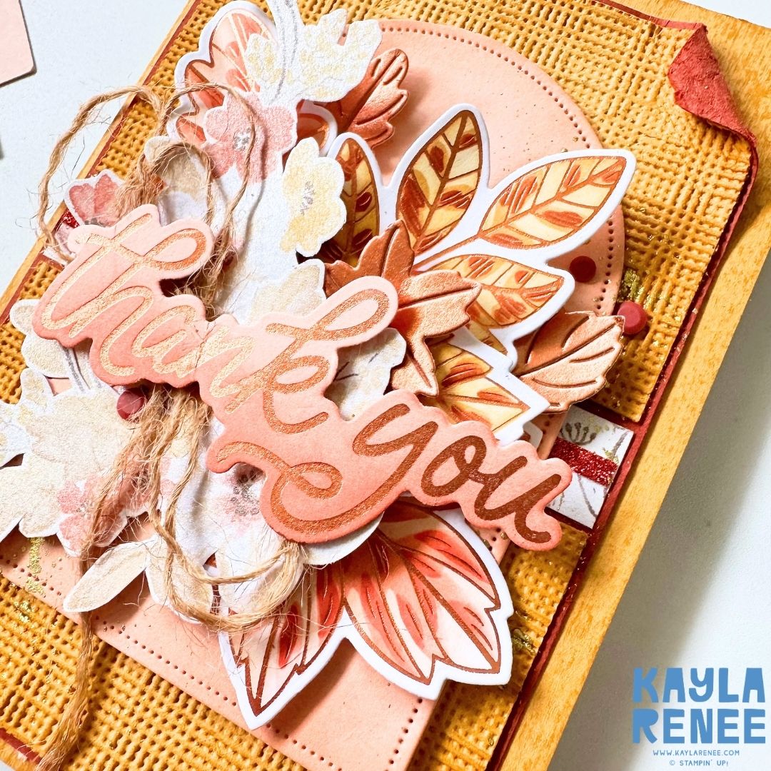 Close-up of an autumn-themed handmade card with layered leaves and flowers, copper hot foil accents, textured background and natural twine. The card features a large “Thank you” sentiment and uses Stampin’ Up! Lustrous Leaves Hot Foil Dies and Glow of Harvest Specialty Designer Series Paper.