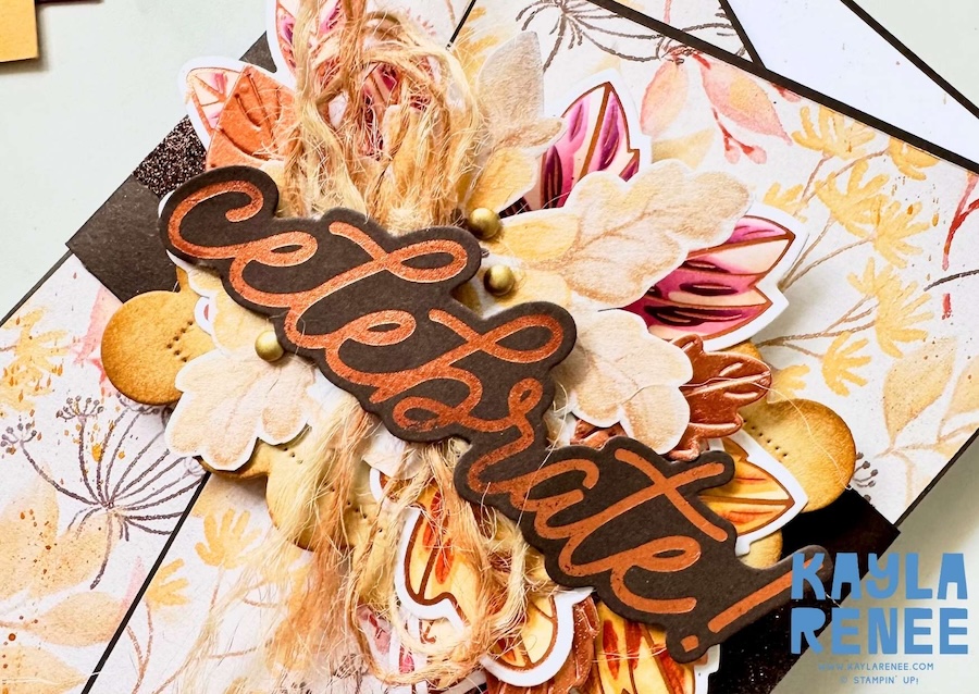 Close-up of an angled gatefold card decorated with autumnal patterned paper, layered flowers and leaves, natural twine and copper hot foil accents. The raised “Celebrate!” sentiment is the focal point
