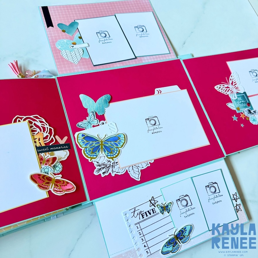 Open mini album spread featuring multiple photo mats and interactive scrapbook elements on bright pink pages, decorated with colourful butterflies, flowers, hearts and layered embellishments.