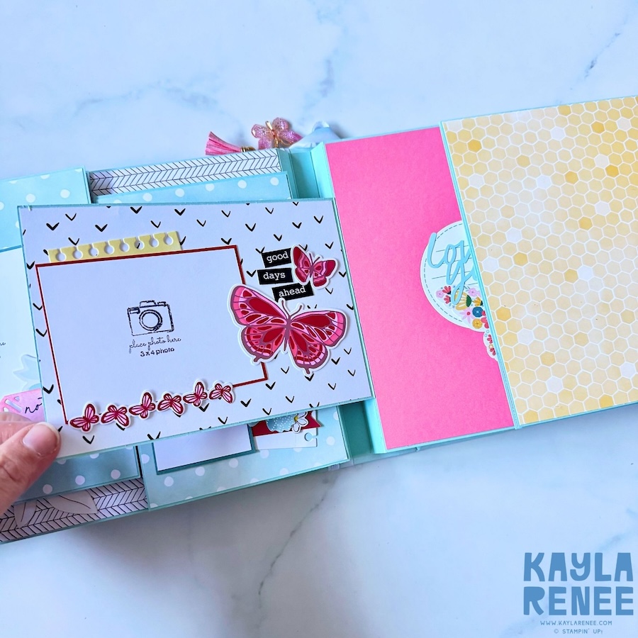 Interactive mini album page with a 3-by-4-inch photo mat decorated with pink butterflies, a floral border and a “good days ahead” sentiment, with additional patterned pages visible behind it.