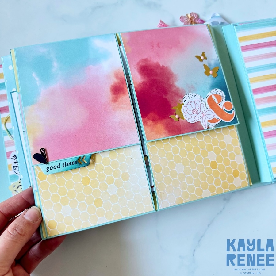 Open mini album spread featuring soft pink and blue watercolour-style patterned paper, small butterfly embellishments and layered decorative elements designed for photos and memories.