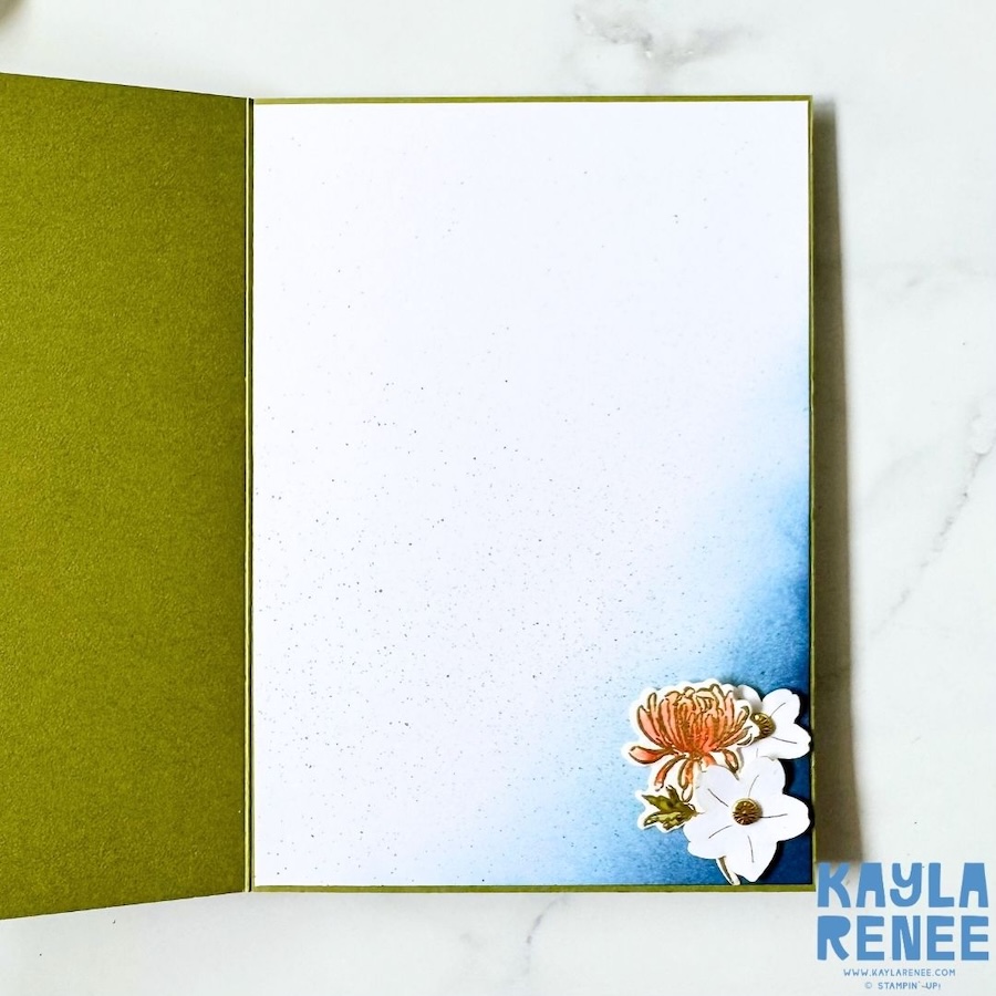 Inside view of the double flip book card showing a large white writing panel with blue shading and a cluster of floral embellishments in the lower corner.