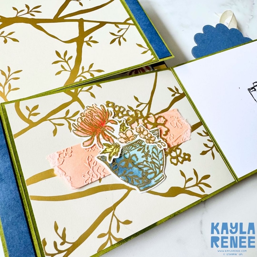 Close-up of an interior section of the double flip book card featuring a floral vase embellishment layered over gold branch-patterned paper and a textured pink strip.