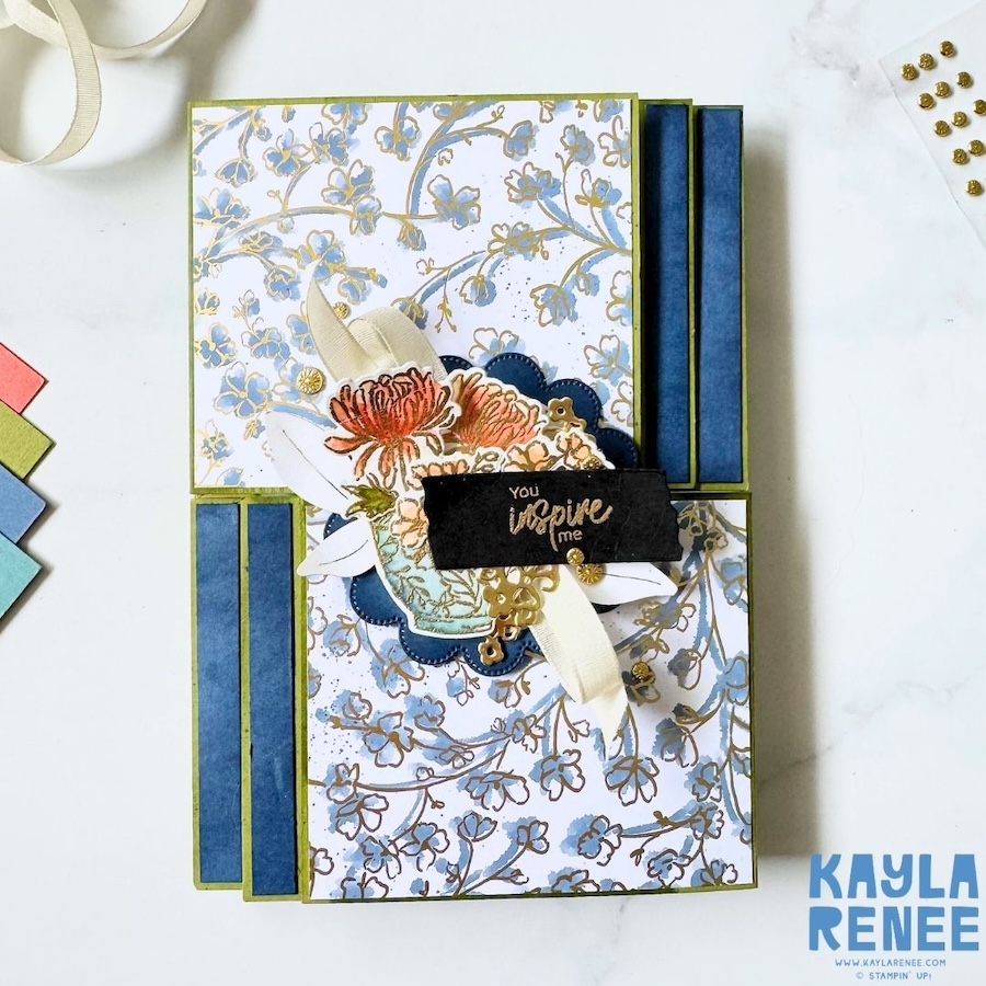 Front view of a handmade double flip book card featuring the Stampin’ Up! Kintsugi Inspirations Suite, with blue and gold floral patterned paper, layered floral embellishments, a decorative vase, cream ribbon and gold accents.